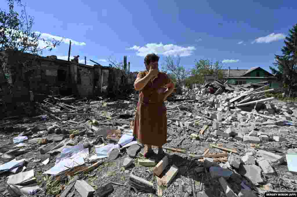 Tatyana Skrypnikova, 60, who sustained light shrapnel wounds, stands among debris of her neighbors&#39; house destroyed following a shelling in the village of Zaoskillya, near Kupyansk, Kharkiv region.