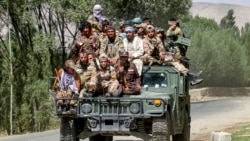 Armed Taliban security personnel ride along a street in the Khash district of Badakhshan Province in 2024.