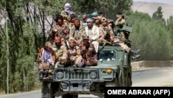 Armed Taliban security personnel ride along a street in the Khash district of Badakhshan Province in 2024.