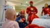 Berat Rexhepaj (left) and several costumed superheroes greet a young patient.