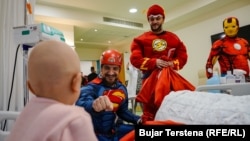 Berat Rexhepaj (left) and several costumed superheroes greet a young patient.