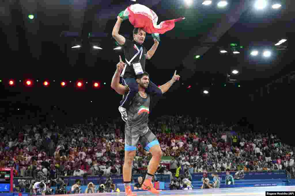 Mohammadhadi Saravi of Iran celebrates with his coach after defeating Armenia&#39;s Artur&nbsp;Aleksanian&nbsp;during their men&#39;s Greco-Roman 97-kilogram final wrestling match on August 7.