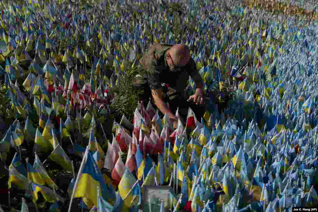 Polish Army veteran Slawomir Wysocki places the country&#39;s flag at a memorial site in Kyiv to honor a Polish paramedic killed in Ukraine&#39;s war against Russia.