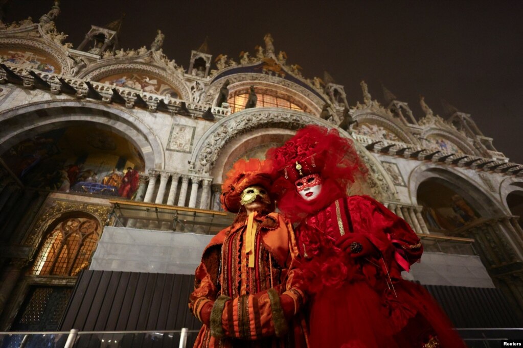 Një çift i maskuar duke ecur pranë një ndërtese në Sheshin e Shën Markut në Venedik.