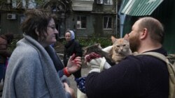 Local residents stand next to an apartment building hit by a Russian missile strike in Dnipro on April 19.