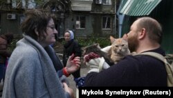 Local residents stand next to an apartment building hit by a Russian missile strike in Dnipro on April 19.