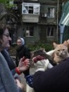 Local residents stand next to an apartment building hit by a Russian missile strike in Dnipro on April 19.