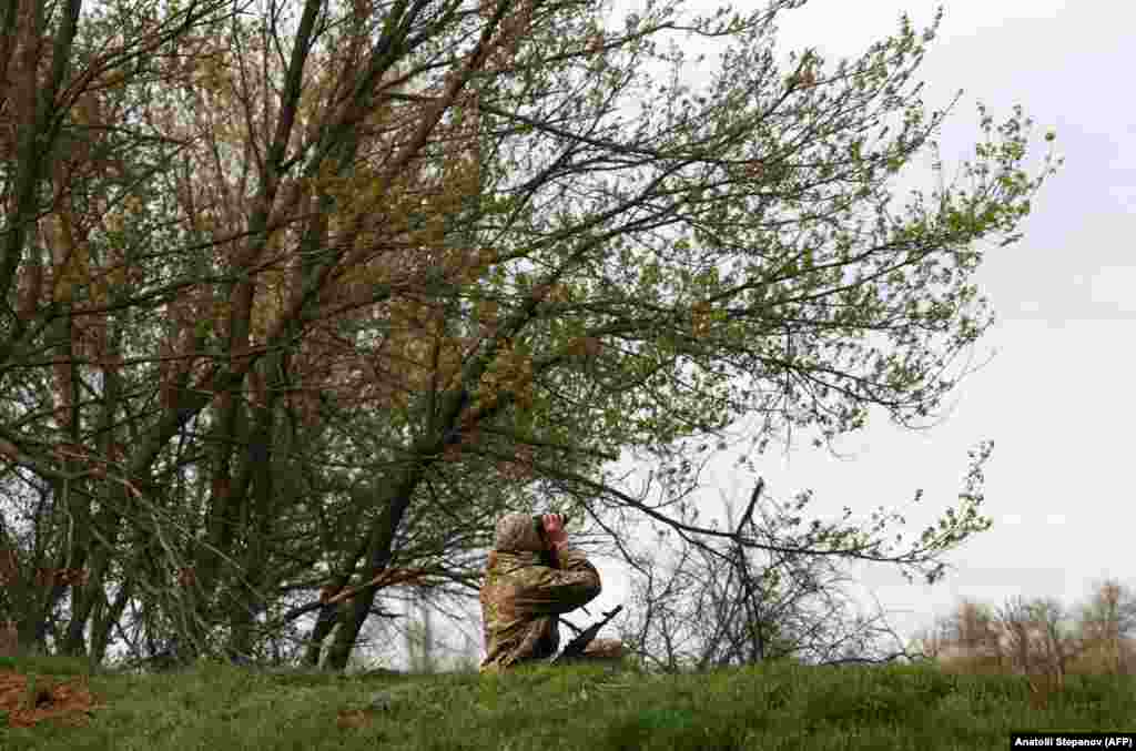 A Ukrainian soldier scans the sky with binoculars...