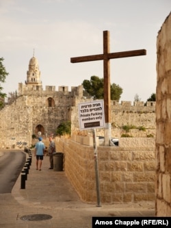A sign in English and Hebrew, erected by XANA Capital at the entrance to Jerusalem's Cow's Garden car park. The wooden cross was placed by unidentified workmen on June 13, then removed by Israeli police the following day.