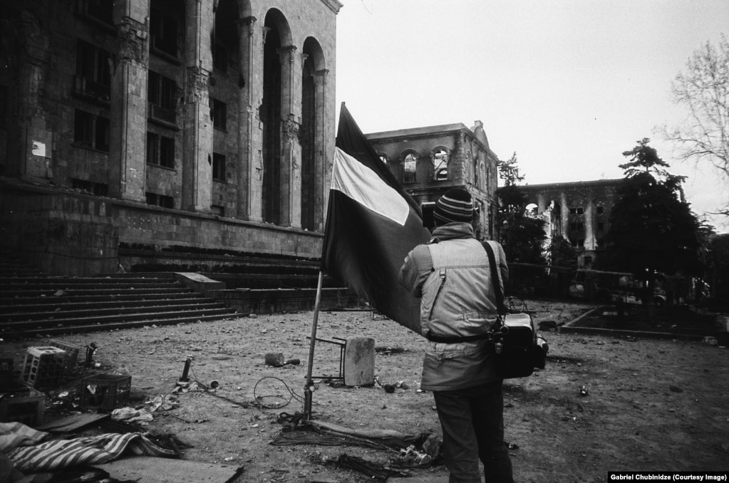 Un giornalista visivo riprende la scena davanti al parlamento georgiano.