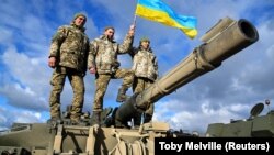 Украинские военнослужащие позируют на танке Challenger 2 на военной базе Bovington Camp на юго-западе Великобритании, 22 февраля 2023 года