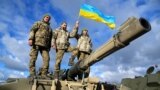 U.K. – Ukrainian personnel hold a Ukrainian flag as they pose on top of a Challenger 2 tank during training at Bovington Camp, near Wool in southwestern Britain, February 22, 2023