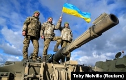 Українські військовослужбовці позують на танку Challenger 2 на військовій базі Bovington Camp на південному заході Великої Британії, 22 лютого 2023 року
