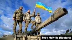 Украинские военнослужащие позируют на танке Challenger 2 на военной базе Bovington Camp на юго-западе Великобритании, 22 февраля 2023 года