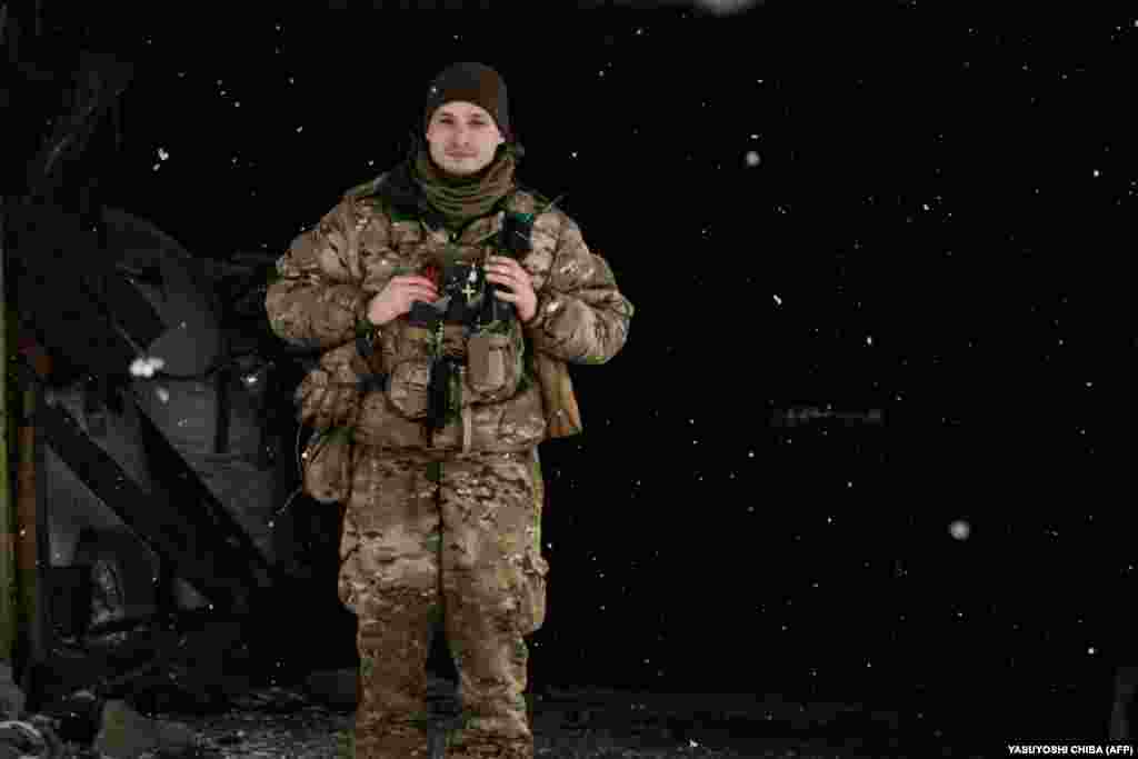 A mortarman surveys the frozen and battle-scarred landscape near his shelter as snow falls. &nbsp;