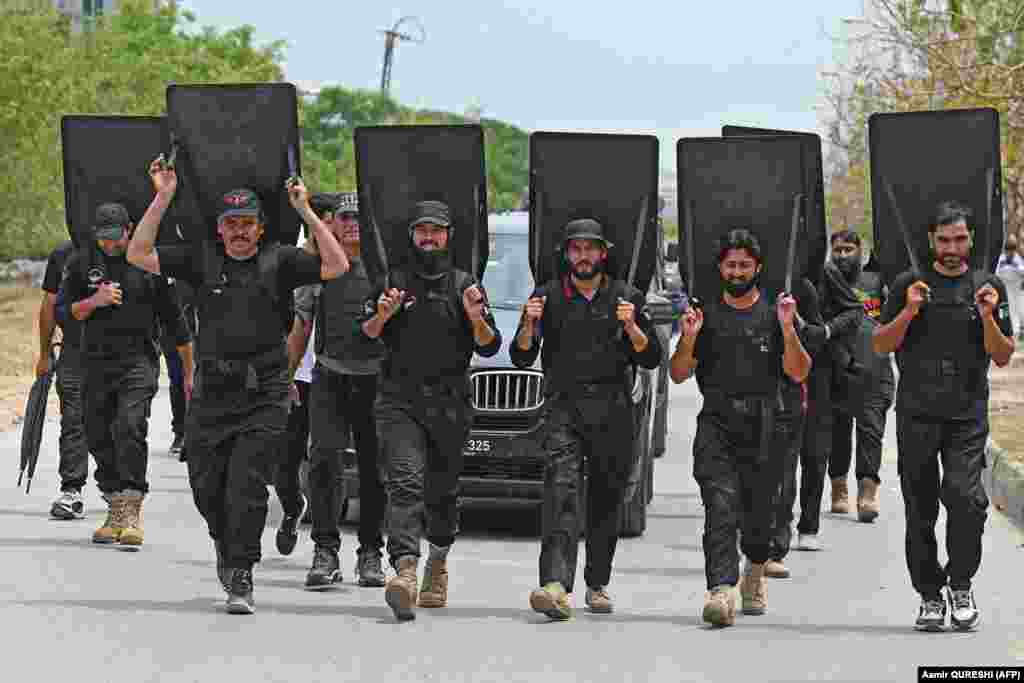 Pakistani security personnel with ballistic shields escort a vehicle carrying former Prime Minister Imran Khan as he leaves after appearing before an anti-terrorism court in Islamabad on May 23.