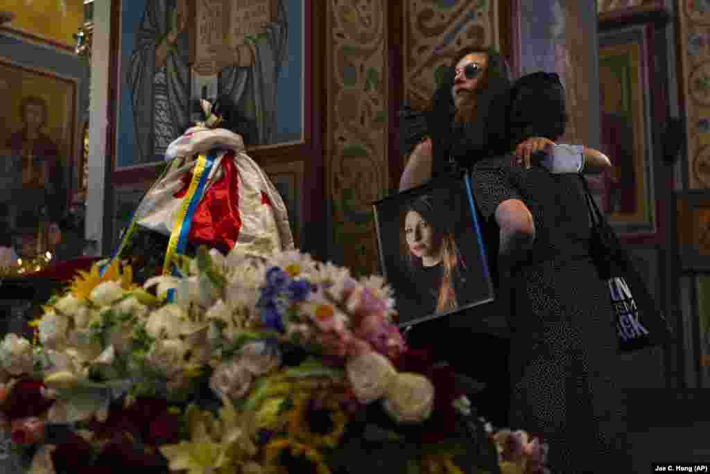 Holding a photo of Ukrainian writer Viktoria Amelina, Sofia Chelyak hugs a woman during a memorial service for Amelina in Kyiv. The award-winning writer was killed last week by a Russian missile attack on a popular restaurant frequented by journalists and aid workers in eastern Ukraine.&nbsp;