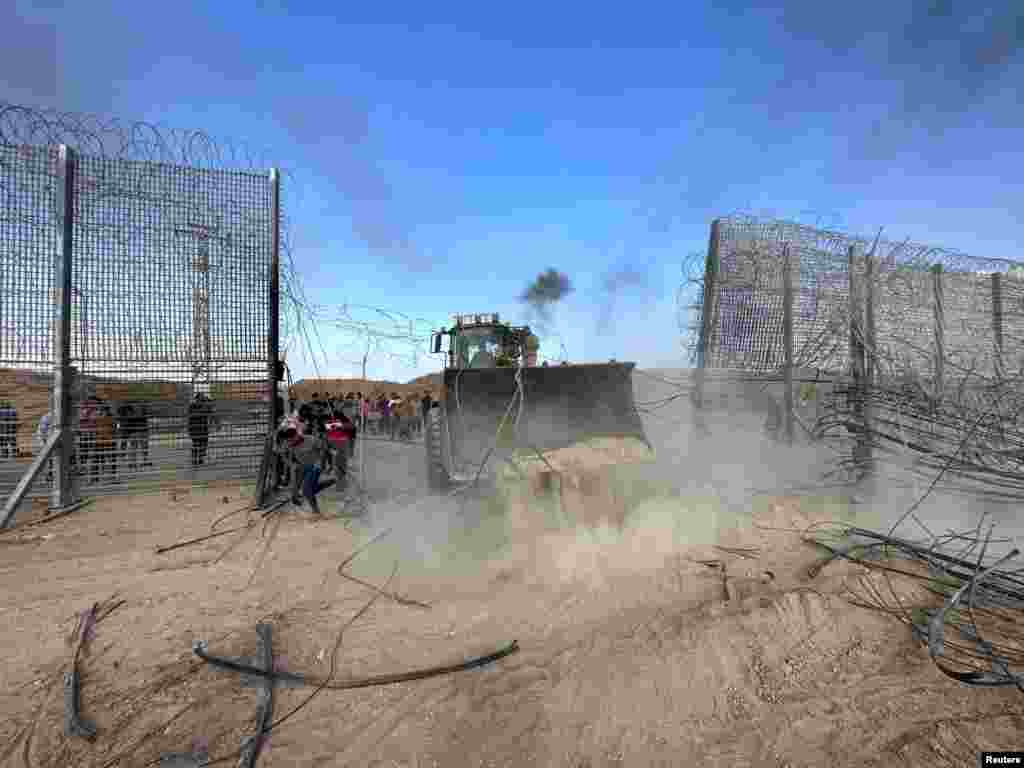 Palestinians break into the Israeli side of the Israel-Gaza border fence on October 7, 2023. The extremist group Hamas carried out an unprecedented, multi-pronged attack on Israel, firing thousands of rockets as dozens of Hamas fighters infiltrated the heavily fortified border in several locations by air, land, and sea and catching the country off-guard on a major holiday.