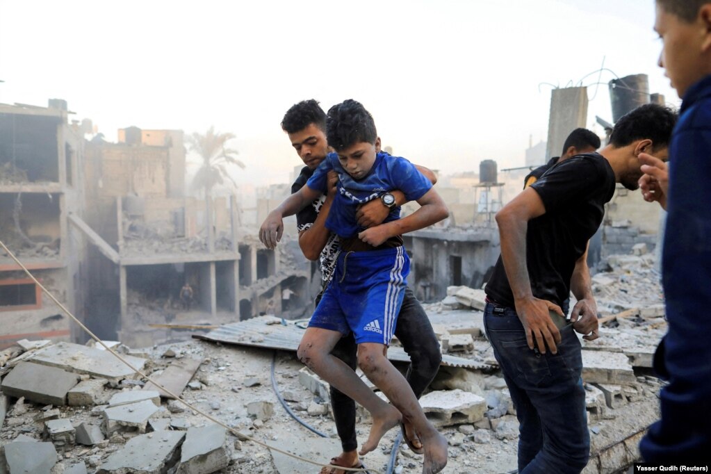 Një burrë mban një fëmijë të plagosur në vendin e një sulmi izraelit në Khan Younis, më 19 tetor 2023.