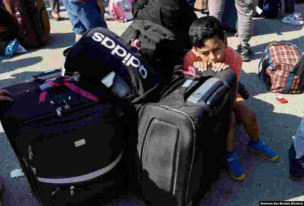 Egy palesztin kisfiú csomagokon pihen&nbsp;az Egyiptommal közös rafahi határátkelőhelynél, abban a reményben, hogy a családja engedélyt kap a Gázai övezet elhagyására. A felvétel 2023. október 16-án készült