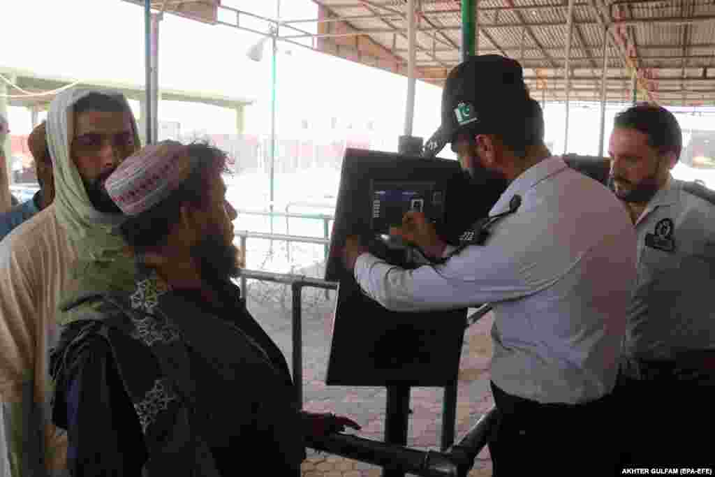 An officer checks documents of people crossing into Afghanistan at the border. &nbsp;