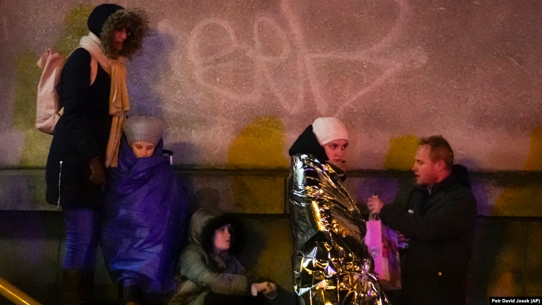 Câțiva oameni se adăpostesc lângă clădirea Facultății de Filosofie a Universității Caroline din centrul orașului Praga, Cehia, pe 21 decembrie 2023, după un atac armat în care au fost ucise 14 persoane.