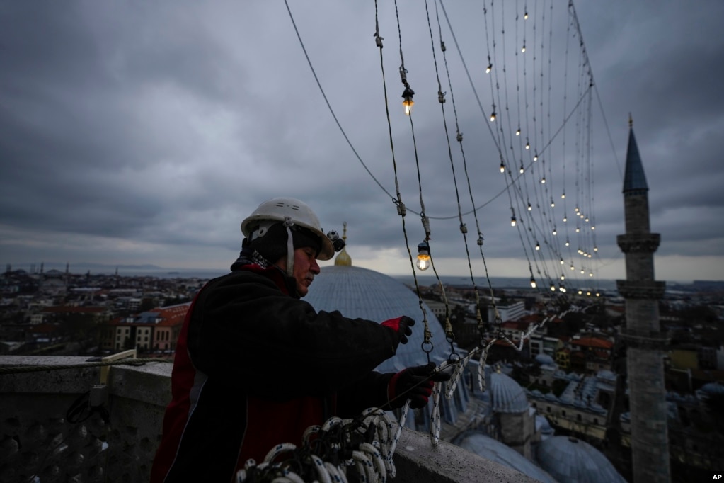 Mjeshtri i Mahyas Cemil Buyurkan duke vendosur një mesazh të bërë me drita në një prej&nbsp; minareve të Xhamisë së Sulejmanit në Stamboll, Turqi