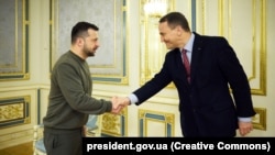 Ukrainian President Volodymyr Zelenskiy (left) greets Polish Foreign Minister Radosław Sikorski in Kyiv on December 22.