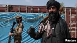 Taliban fighters stand guard while people wait to receive sacks of rice as part of humanitarian aid sent by China, at a distribution center in Kabul. (file photo)