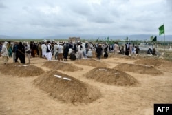Relatives offer prayers during a burial ceremony near the graves of victims who lost their lives following flash floods after heavy rainfall in northern Baghlan Province in May.