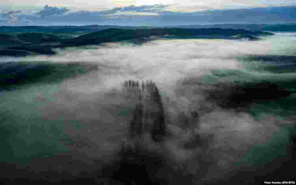 An aerial view taken by a drone shows morning mist lingering above the landscape near the municipality of Cered, northern Hungary.