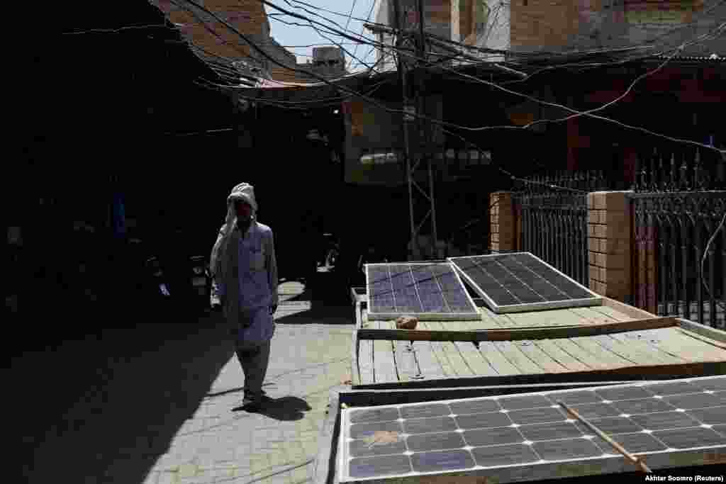 Një burrë duke kaluar pranë paneleve diellore në Xhakobabad. Temperatura më e lartë në Pakistan arriti në 53.7 gradë celsius dhe u regjistrua më 28 maj 2017, në qytetin Turbat, që ndodhet në provincën jugperëndimore të Baluçistanit.&nbsp;