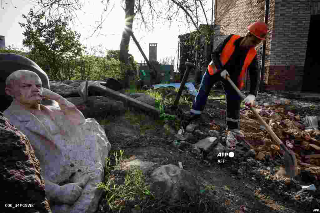 Komunalni radnik čisti krhotine oko skulpture sovjetskog utemeljitelja Vladimira Lenjina u uništenom muzeju lokalne povijesti u Mariupolju, u dijelu Ukrajine koji je trenutačno pod okupacijom Rusije, 15. aprila.