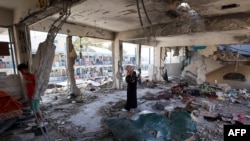 Palestinka stoji usred uništene učionice u školi koju vodi Agencija Ujedinjenih nacija za palestinske izbeglice (UNRWA) pogođene u napadu izraelske vojske dan ranije, u kampu Nuseirat u centralnom pojasu Gaze. 7. juna 2024.
