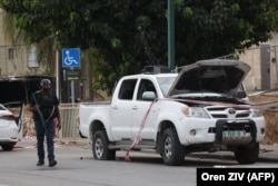 Pripadnik izraelskih snaga sigurnosti prolazi pored vozila s montiranim oružjem koje su za sobom ostavili palestinski militanti u južnom gradu Sderotu 7. oktobra 2023.