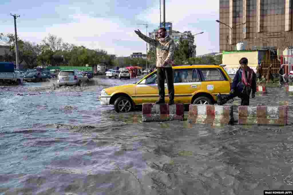 An Afghan traffic policeman gestures while on duty on a flooded road in Kabul.&nbsp;