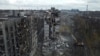 An excavator demolishes an apartment block destroyed during the fighting in Mariupol. 