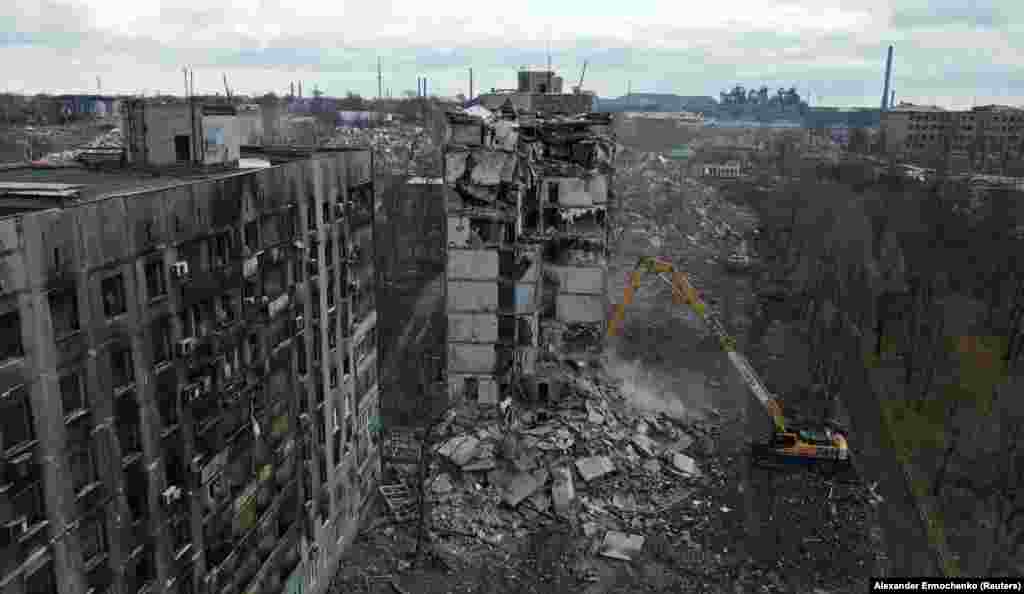 Një ekskavator shkatërron një bllok apartamentesh të rrënuara në Mariupol, më 15 shkurt, 2023. Kjo fotografi dhe gjashtë të tjera më poshtë të fotografit Alexander Ermochenko u bënë nga fillimi deri në mes të shkurtit 2023, por u publikuan nga Reuters më 22 shkurt.