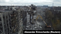 An excavator demolishes an apartment block destroyed during the fighting in Mariupol. 