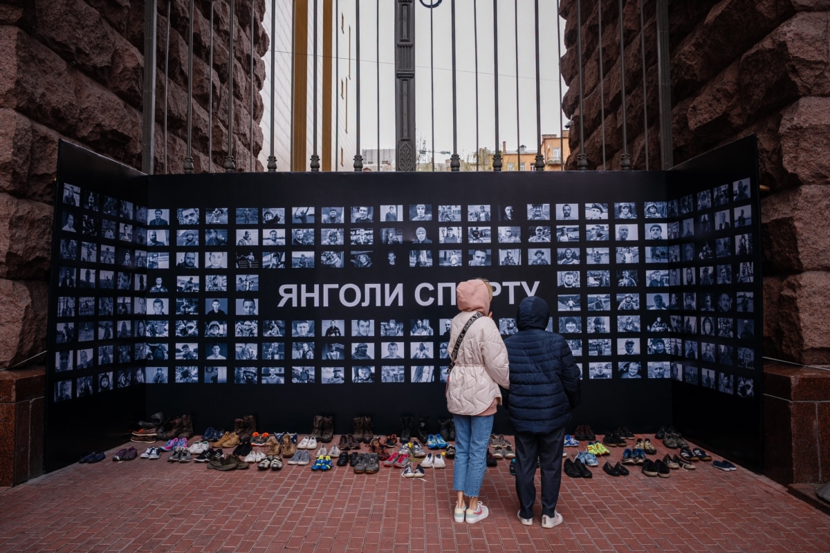 Women look at a wall of photographs of two hundred Ukrainian athletes killed in Russia's invasion of Ukraine, at an exhibition titled "Angels of Sport" in Kyiv, April 18, 2023.