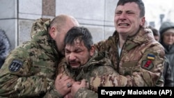 Ukrajinski vojnici plaču kraj kovčega jednog druga tokom njegove sahrane na Trgu nezavisnosti u Kijevu 15. decembra 2023.