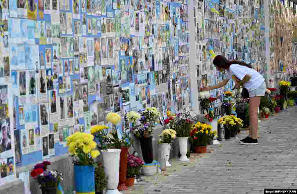 A girl touches a photograph of a relative on the Memory Wall of Fallen Defenders of Ukraine in Kyiv.