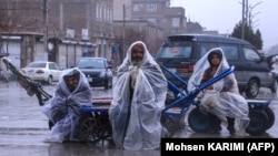 په هرات کې خلکو د باران مهال په خپلو لاسي کراچیو کې ناست دي ـ د مارچ ۱۲مې انځور.