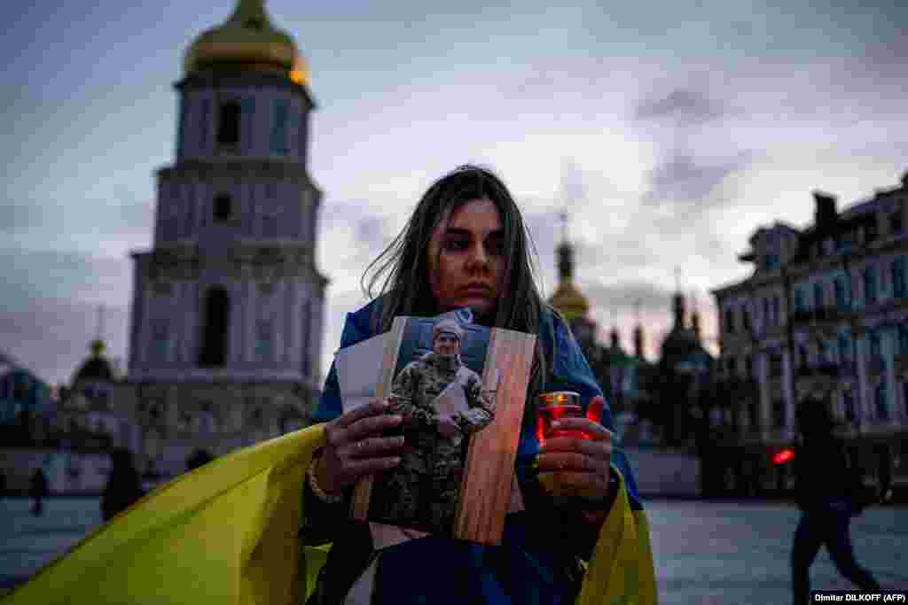 A woman holds a candle and a portrait of her husband, who was captured during the siege of the port city of Mariupol, during a rally in tribute to defenders of Ukraine as part of Volunteer Day, in Kyiv on March 14.