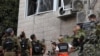 Израильские силы безопасности осматривают повреждения здания в арабо-израильском городе Абу-Гош после ракетного обстрела 