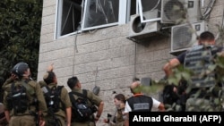 Израильские силы безопасности осматривают повреждения здания в арабо-израильском городе Абу-Гош после ракетного обстрела 
