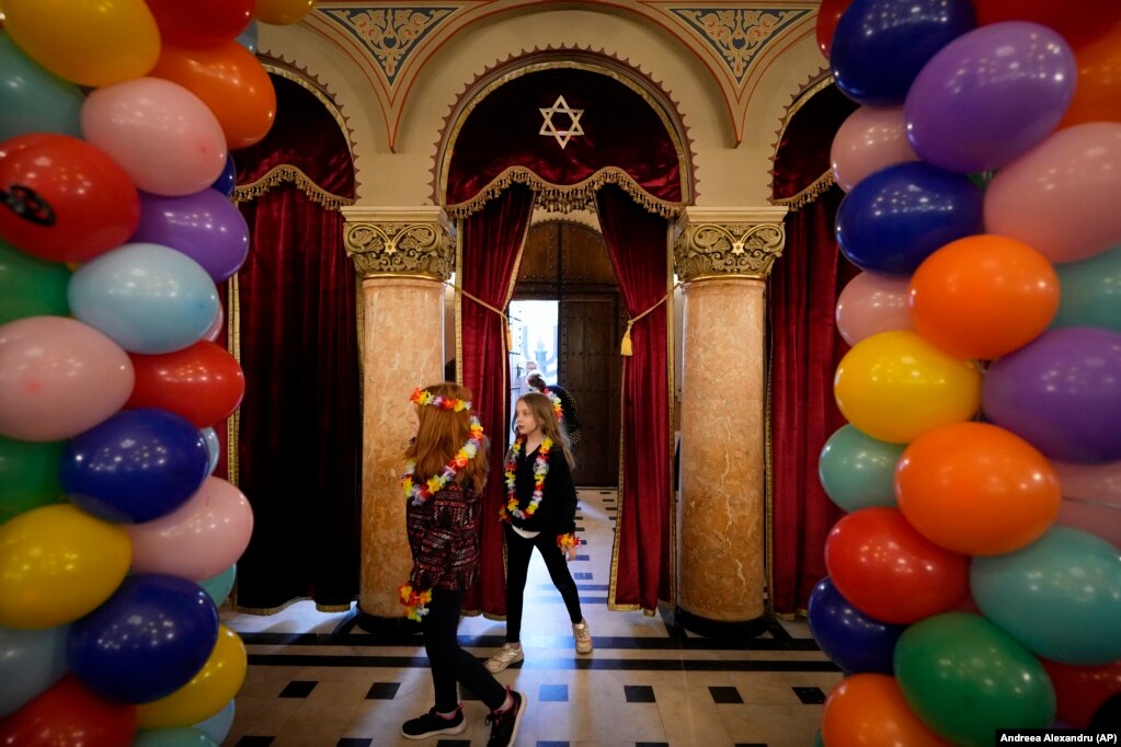 Fëmijë që mbajnë gjerdanë lulesh shumëngjyrëshe hyjnë në sinagogën e Tempullit Koral ndërsa komuniteti hebre i Rumanisë shënon festën Purim në Bukuresht, Rumani, të hënën, 6 mars 2023. Festa hebraike Purim përkujton shpëtimin e hebrenjve nga gjenocidi në Persinë e lashtë.