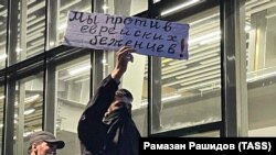 Местный житель держит табличку с надписью: «Мы против еврейских беженцев» во время пропалестинского митинга в аэропорту Махачкалы.