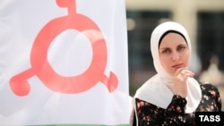 Жительница Ингушетии рядом с флагом республики, иллюстративная фотография
