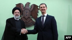 Iranian President Ebrahim Raisi (left) shakes hand with his Syrian counterpart, Bashar al-Assad, in Damascus on May 3. 
